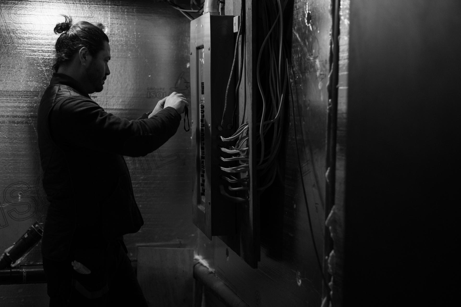 Inspecteur professionnel vérifiant l'installation électrique dans un sous-sol lors d'une inspection prévente